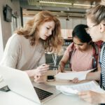 Three women working on paperwork together.