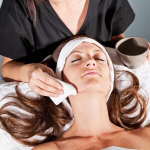 Woman receiving facial with cloth on cheek.