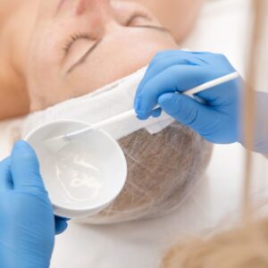 Woman receiving facial treatment with brush.