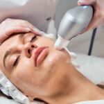 Woman receiving facial treatment with a machine.