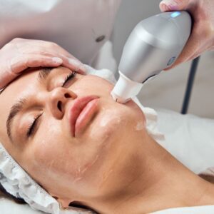 Woman receiving facial treatment with a machine.