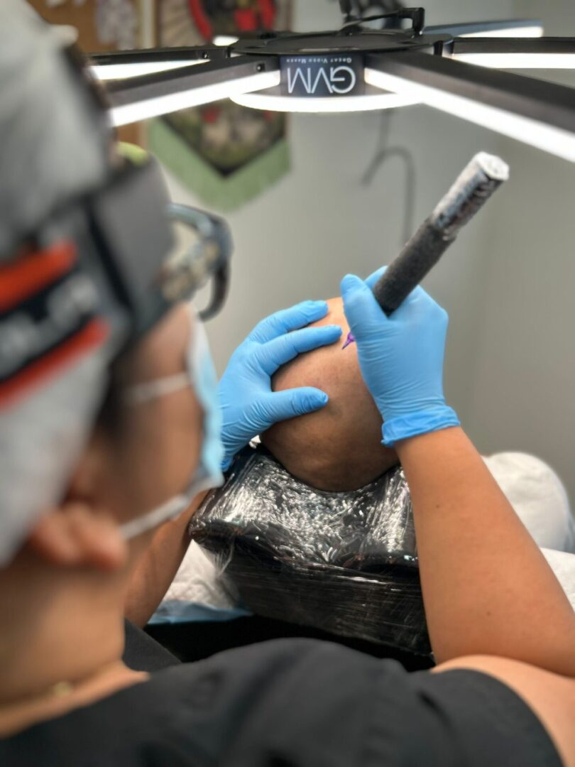 Tattoo artist working on a client's arm.