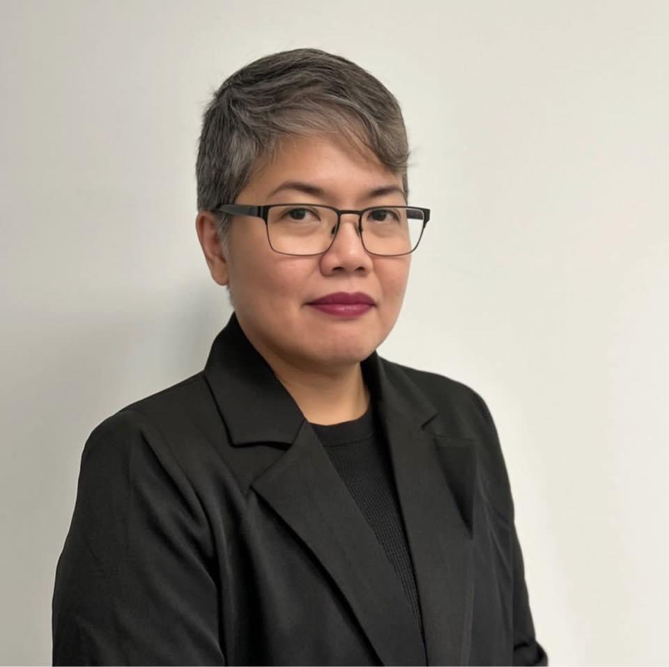 Woman in black blazer and glasses.