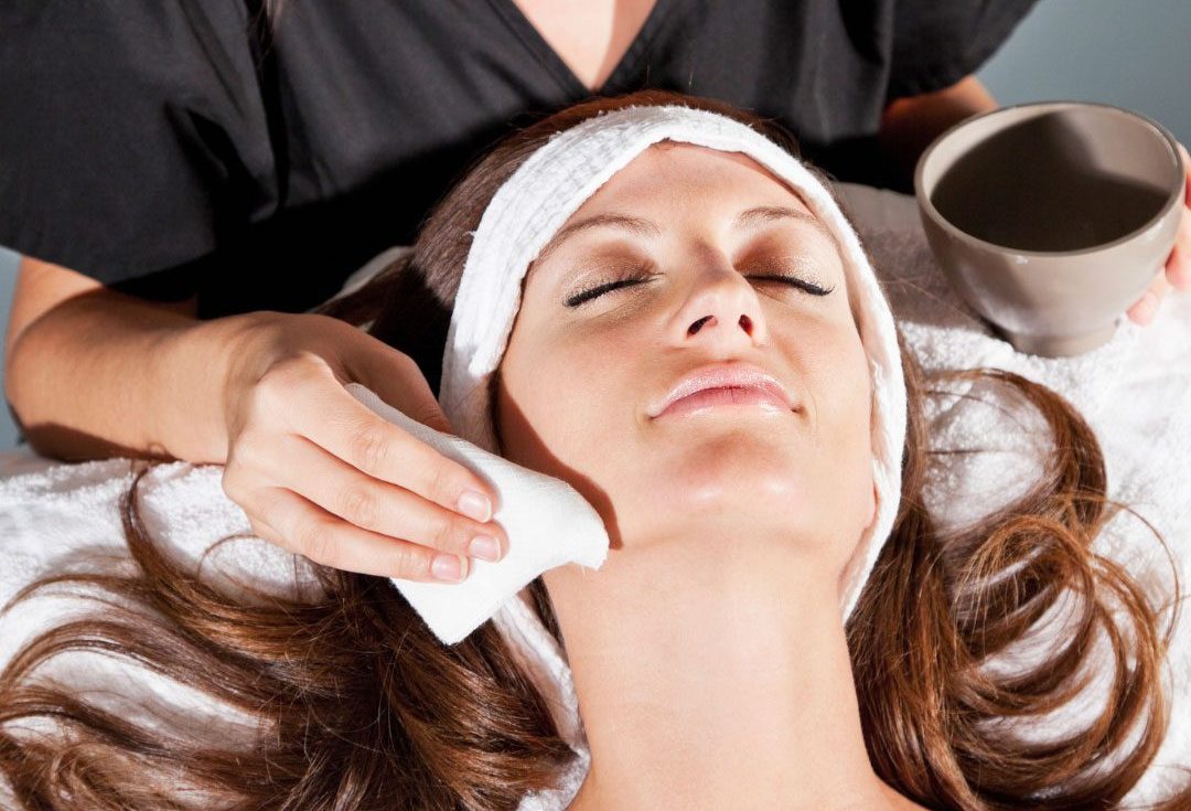 Woman receiving facial with cloth on cheek.